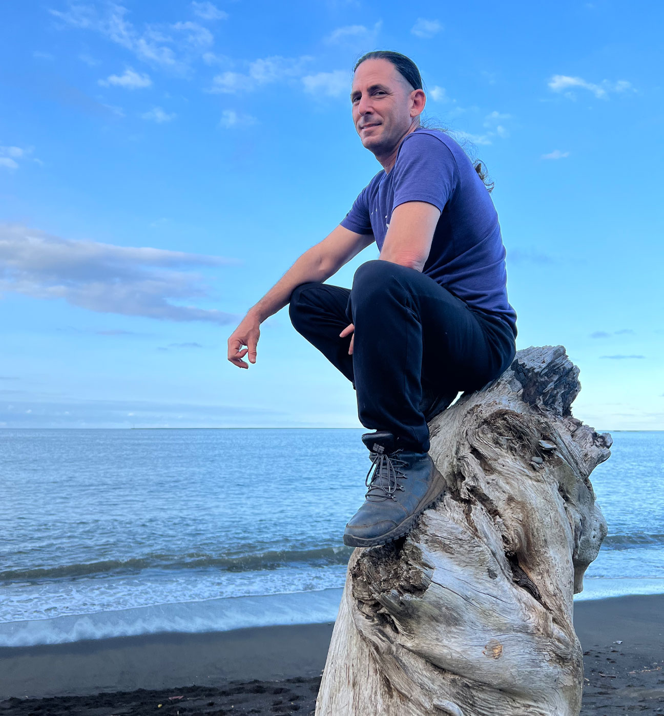 Jeff Primack seated on driftwood by the ocean